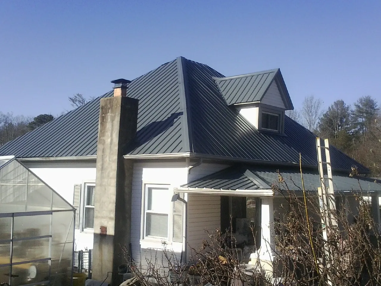Dark blue standing seam metal roof on a white farmhouse with dormer — Slate & Tile Roof Repair by Roofing Brothers in Little Mountain