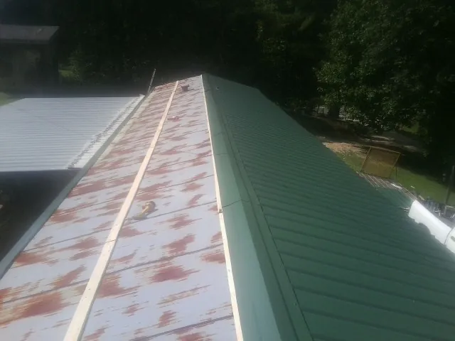 Old rusted panels beside newly installed green metal roofing — Wind Damage Roof Repair by Roofing Brothers in Little Mountain