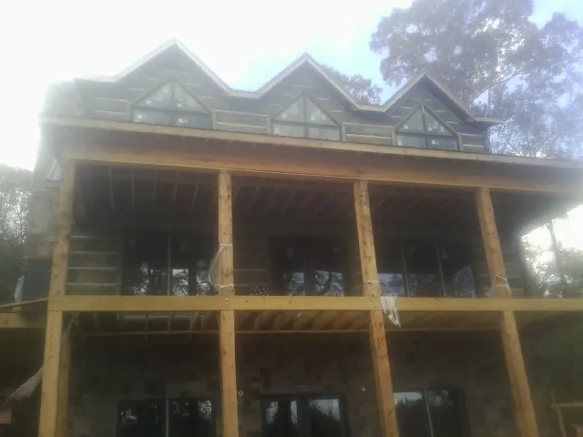 Dormers and porch framing on a large log home under construction — Roof Coating work by our crew in Little Mountain