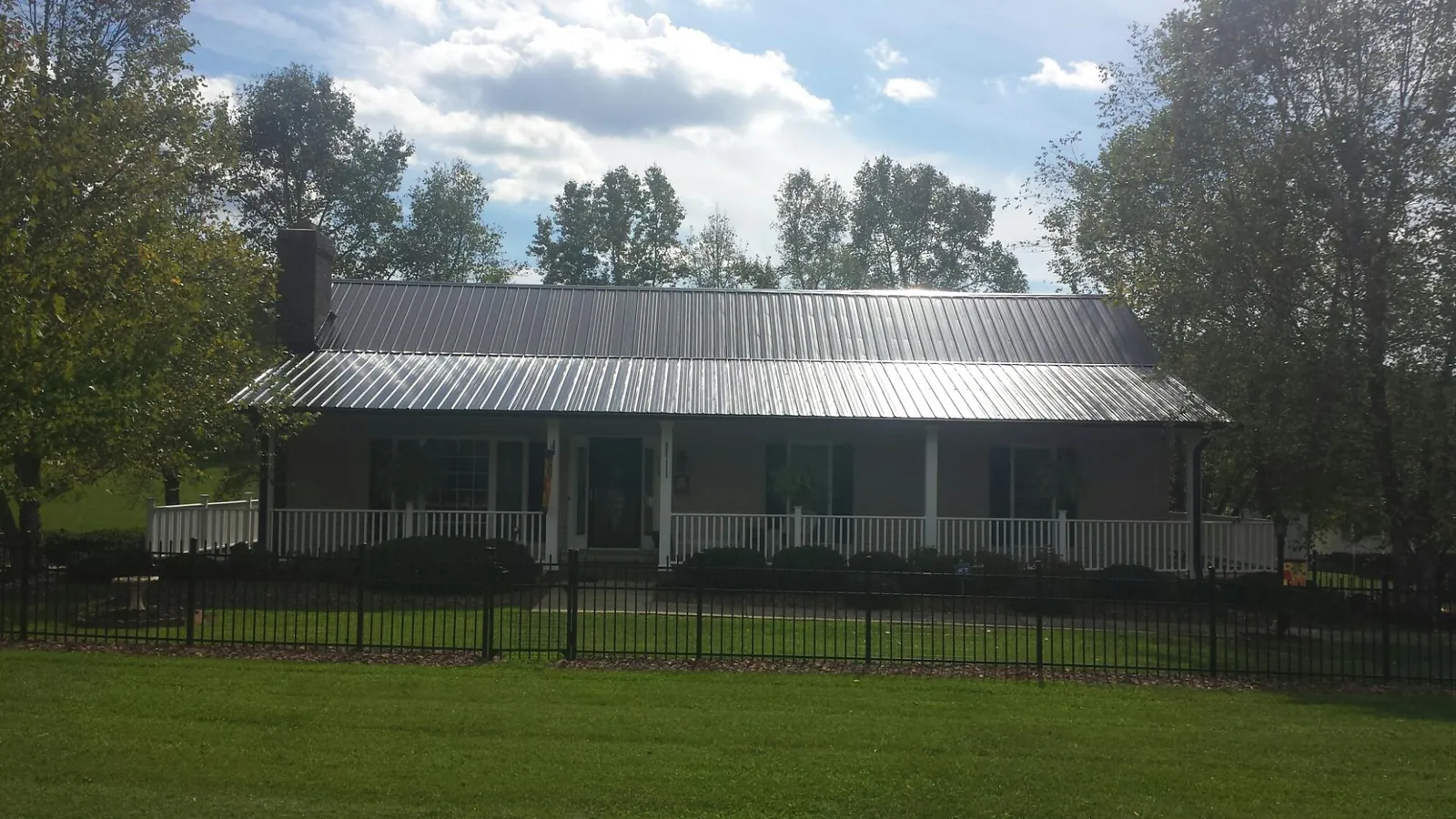 Gray metal roof on a brick ranch with a full width front porch — Gutter Guard Installation work by our crew in Little Mountain