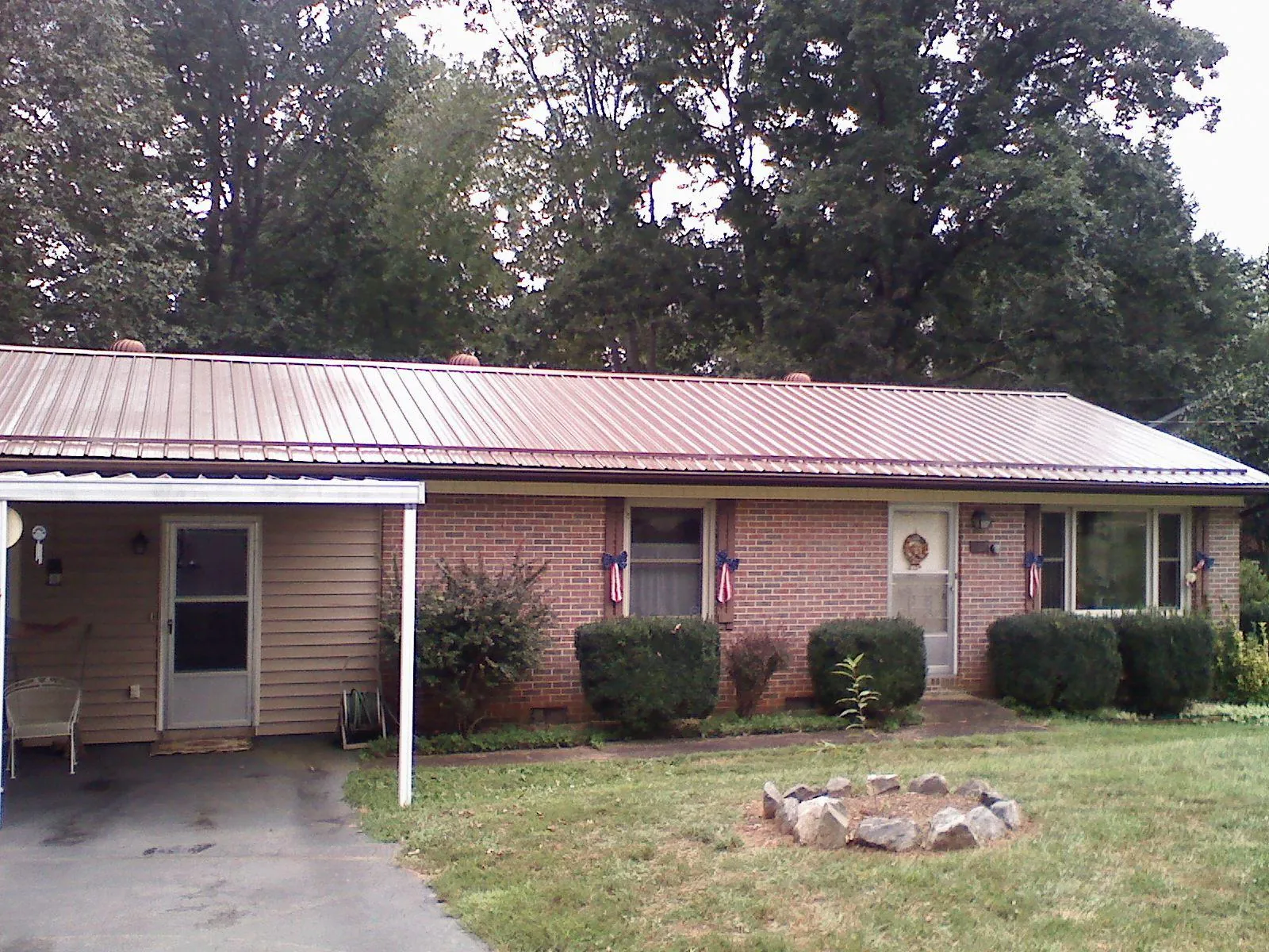 Bronze metal roof and carport on a brick ranch home — Roof Repair work by our crew in Little Mountain