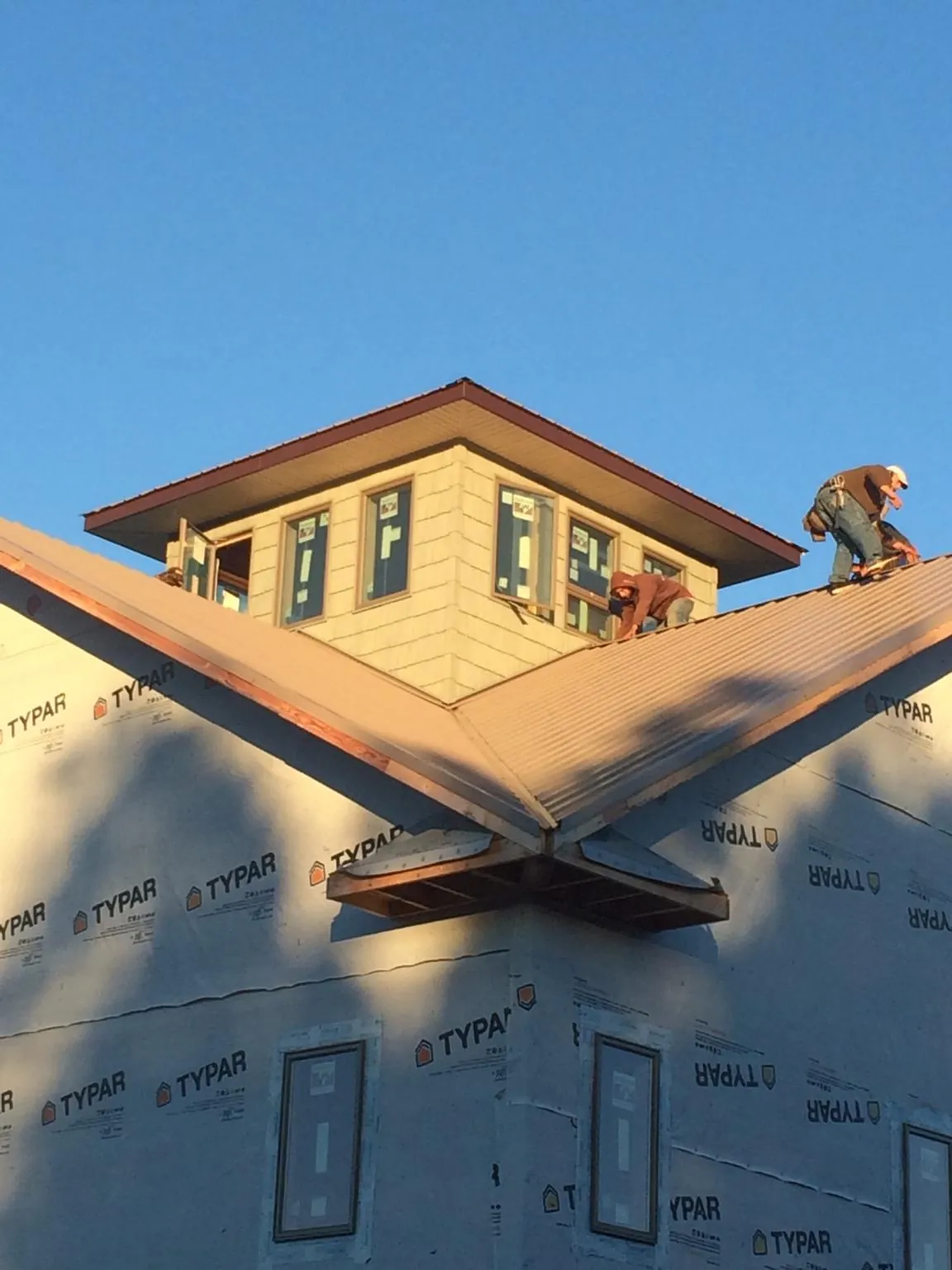 Roofers working around a rooftop cupola on a new metal roof at sunset — Roof Waterproofing in Little Mountain by Roofing Brothers
